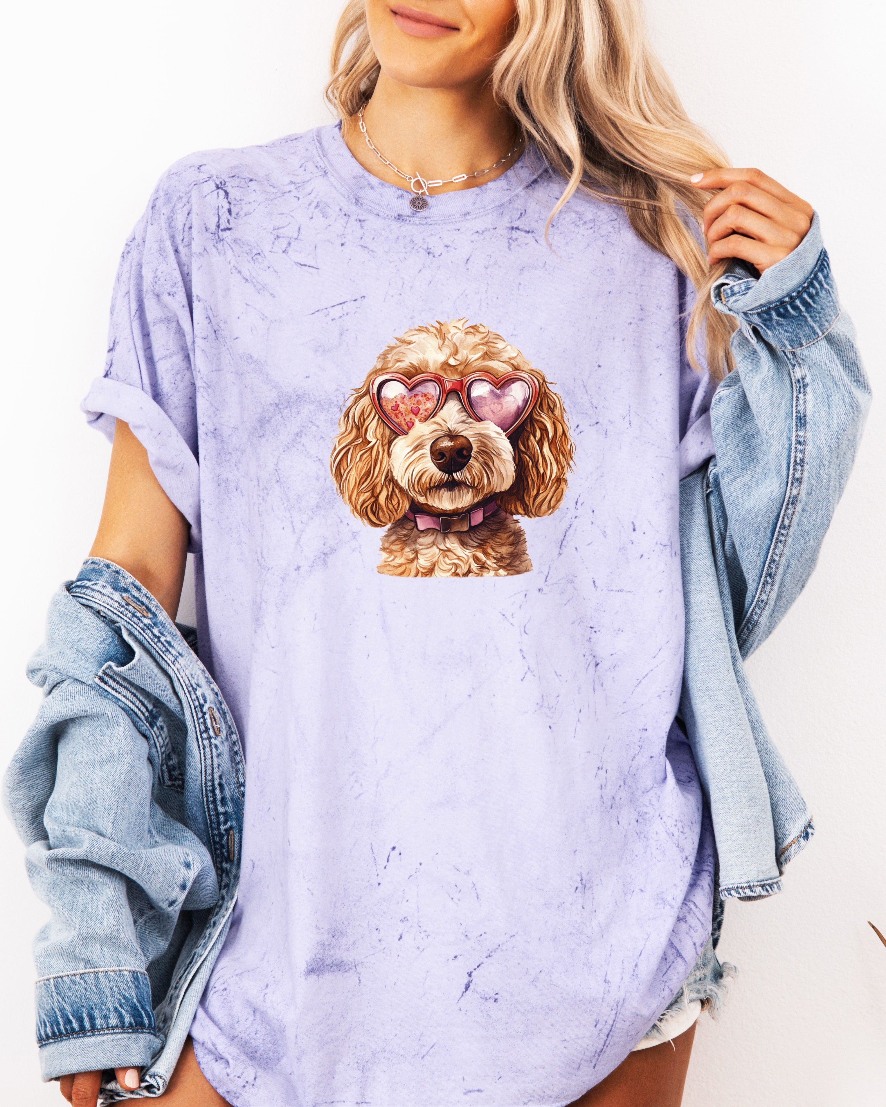 Person wearing a light purple t-shirt with a dog graphic and a denim jacket on a white background