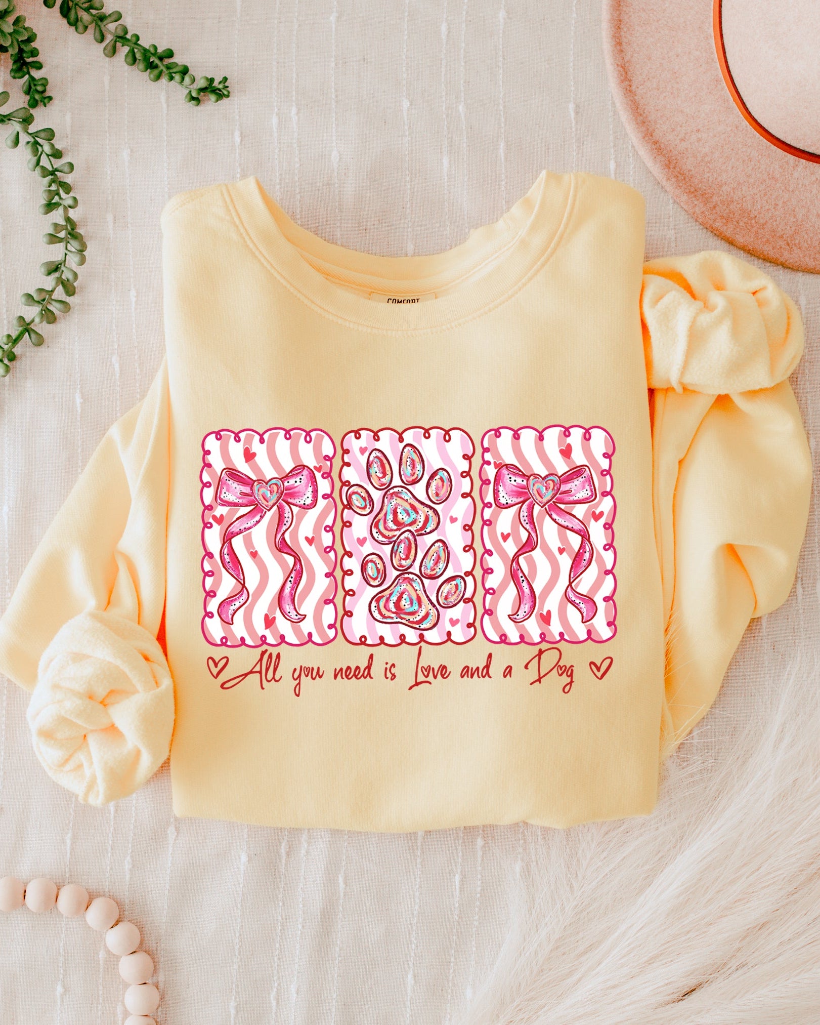 Yellow baby outfit with pink designs and text on a light wooden surface.
