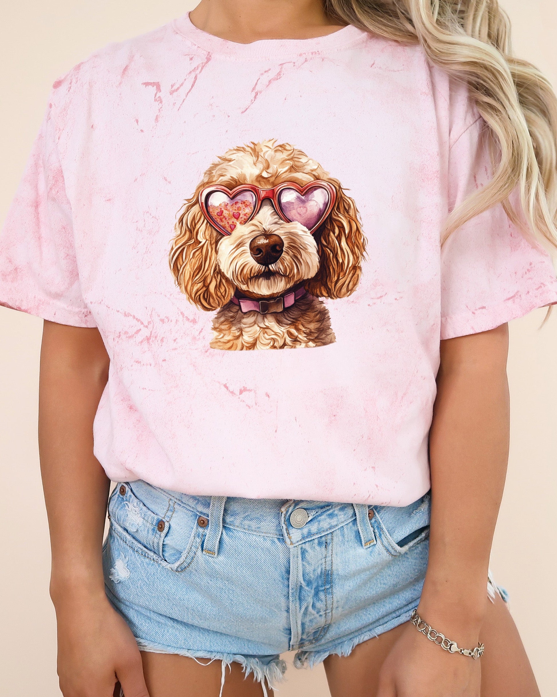 Person wearing a pink t-shirt with a dog graphic and denim shorts on a beige background