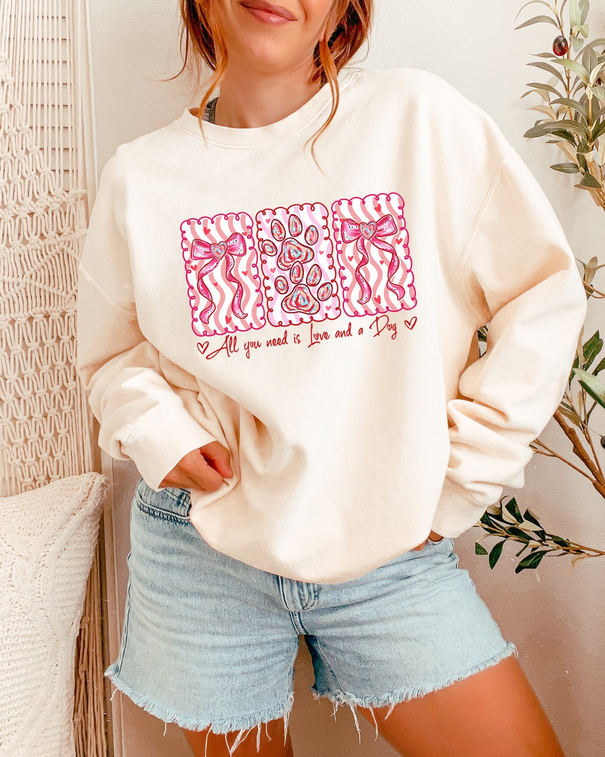 Person wearing a cream sweatshirt with a pink graphic design in a casual setting.