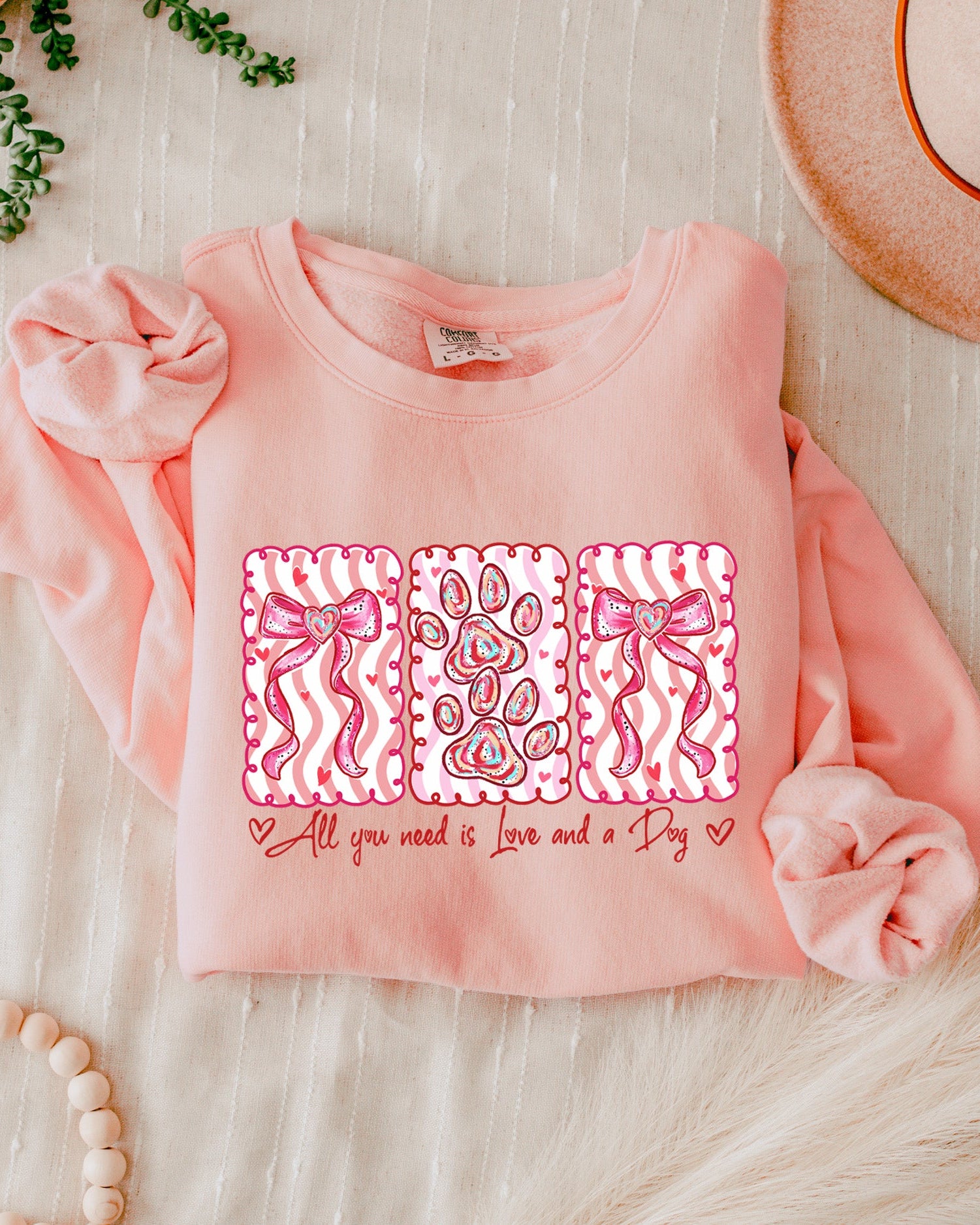 Pink sweatshirt with a graphic design on a light wooden surface